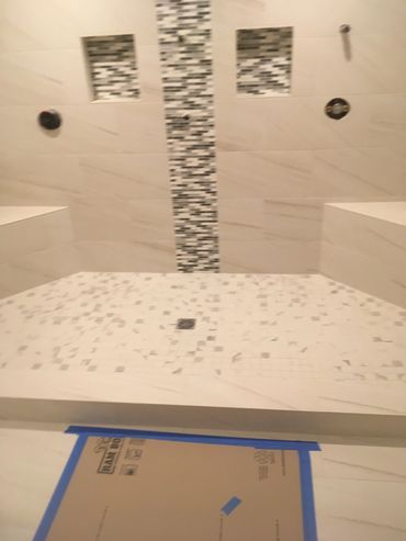 Modern shower with mosaic tile accents and bench seating.