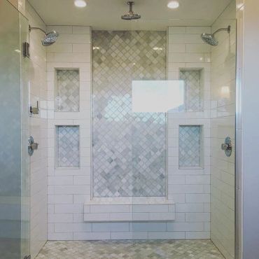Modern spacious shower with dual showerheads and tiled walls.