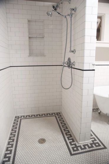 Modern shower with white tiles and black trim.