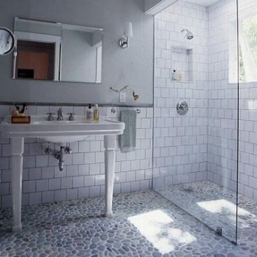 Modern bathroom with pebble stone flooring and glass shower.