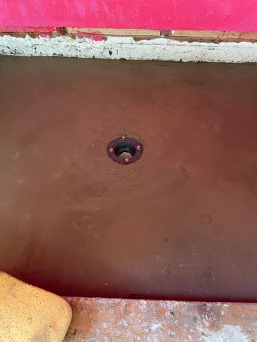 Freshly poured concrete floor with a central drain hole.