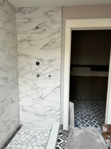 Bathroom under construction with marble tiles and patterned floor.