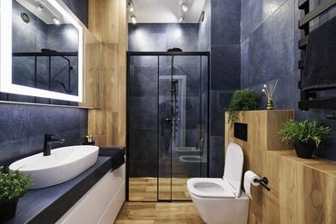 Modern bathroom with dark tiles, wooden accents, and glass shower enclosure.