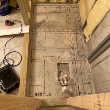 Concrete floor with plumbing and construction markings for renovation.