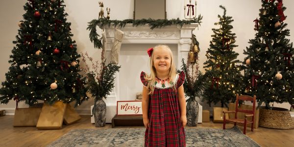 Smiling little girl in a festive red plaid dress during Christmas.
