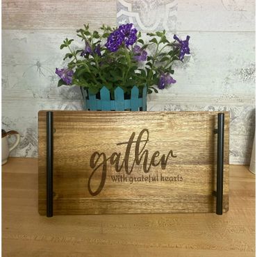 Wooden tray with 'gather with grateful hearts' text and purple flowers in a blue pot.