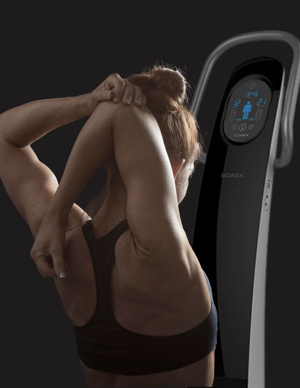 Woman stretching her arm behind her head next to a Sonix fitness device.