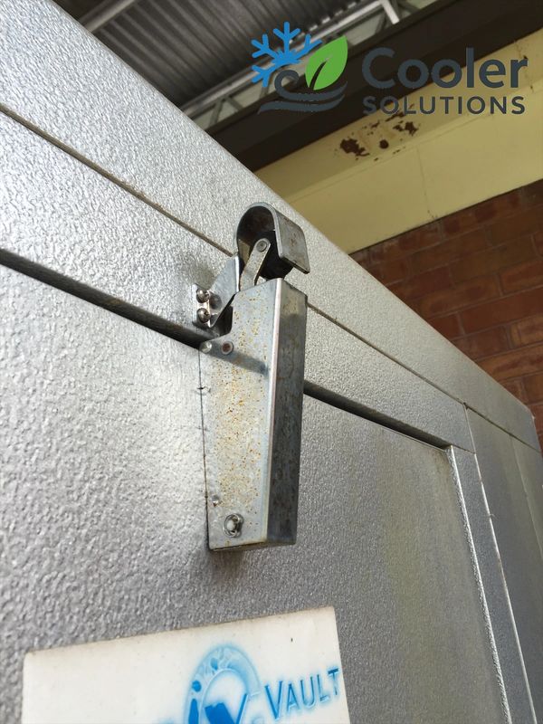 Close-up of a metal latch on a textured cooler door.