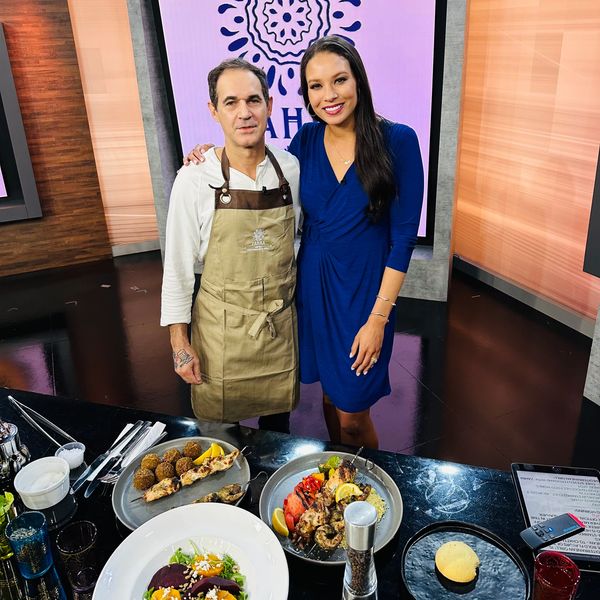 Chef and hostess with prepared dishes in a studio.