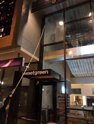 Person cleaning a large window at night.