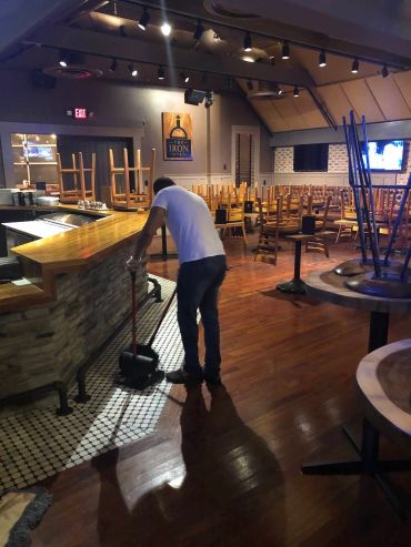 Person cleaning a closed restaurant with chairs on tables.