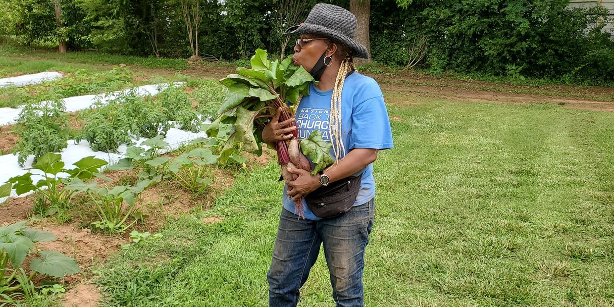 Woman in garden holding large vegetables and kissing leaves.