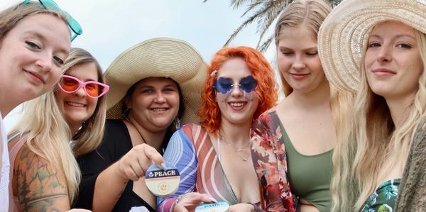 Group of cannabis influencers in bathing suits with cannabis products in hand