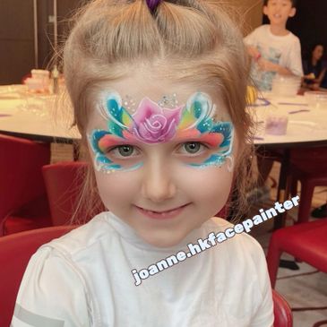 Smiling child with colorful floral face paint design.