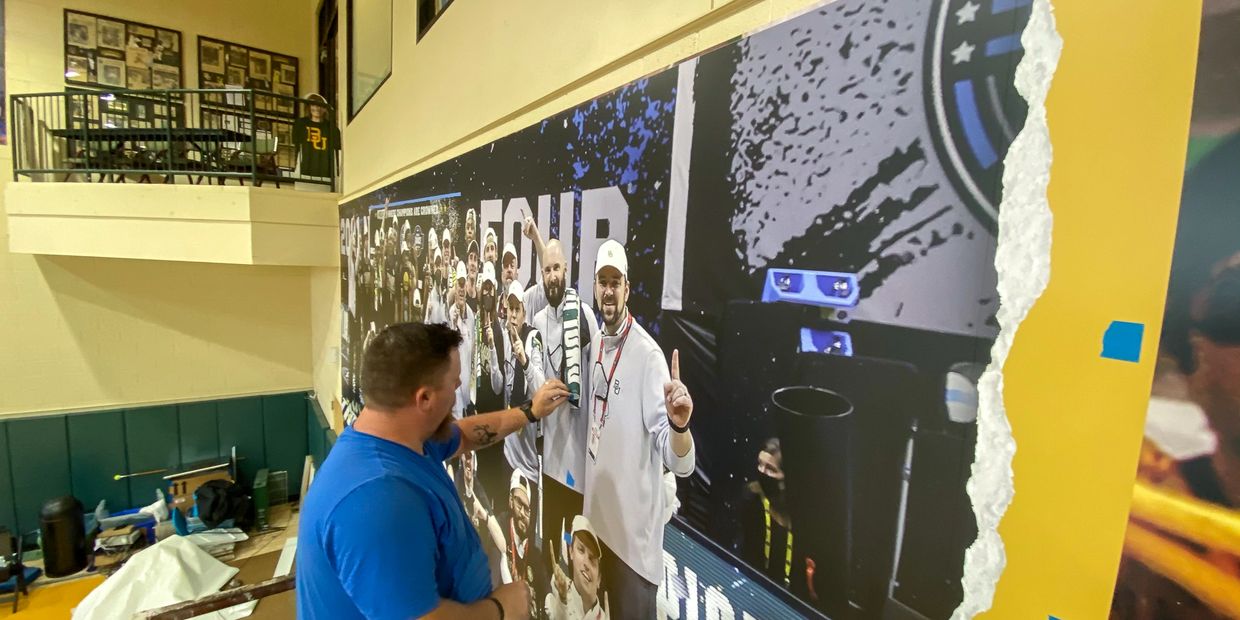 Installing a wall mural in a collegiate basketball gym