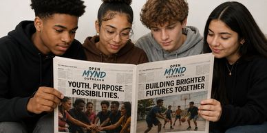 Four young people read a youth-focused newspaper together.