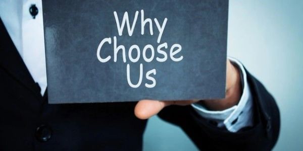 Person in suit holding a sign saying 'Why Choose Us'.