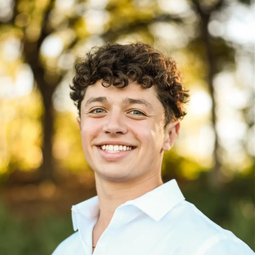 Smiling young man with curly hair outdoors.