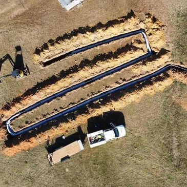 Aerial view of trench digging with pipes and construction equipment.