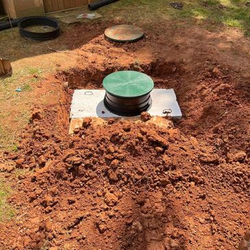 Excavated ground with a green-covered septic tank installation.