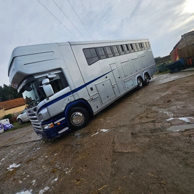 Large silver horsebox truck parked on muddy ground.