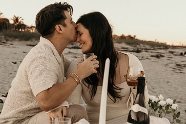 Couple sharing a tender moment during a beachside picnic at sunset.