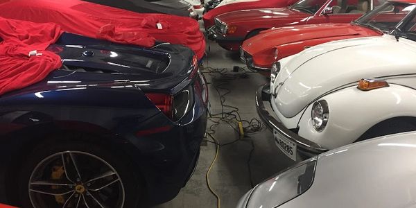classic vehicles in storage hooked up to battery tenders using cords in garage