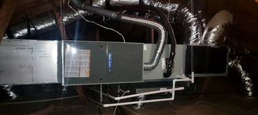 A modern HVAC system installed in an attic with ducts and piping.