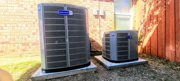 Two American Standard air conditioning units outside a brick house.