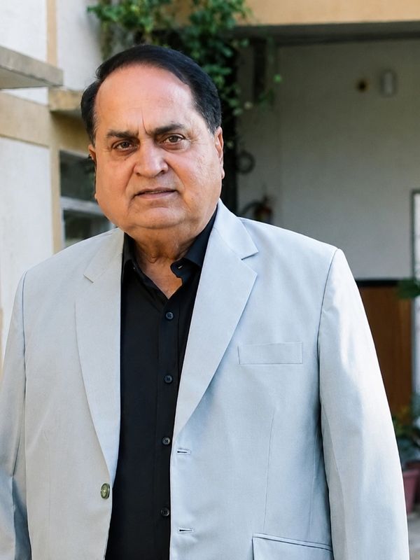 A middle-aged man wearing a light gray blazer and black shirt.