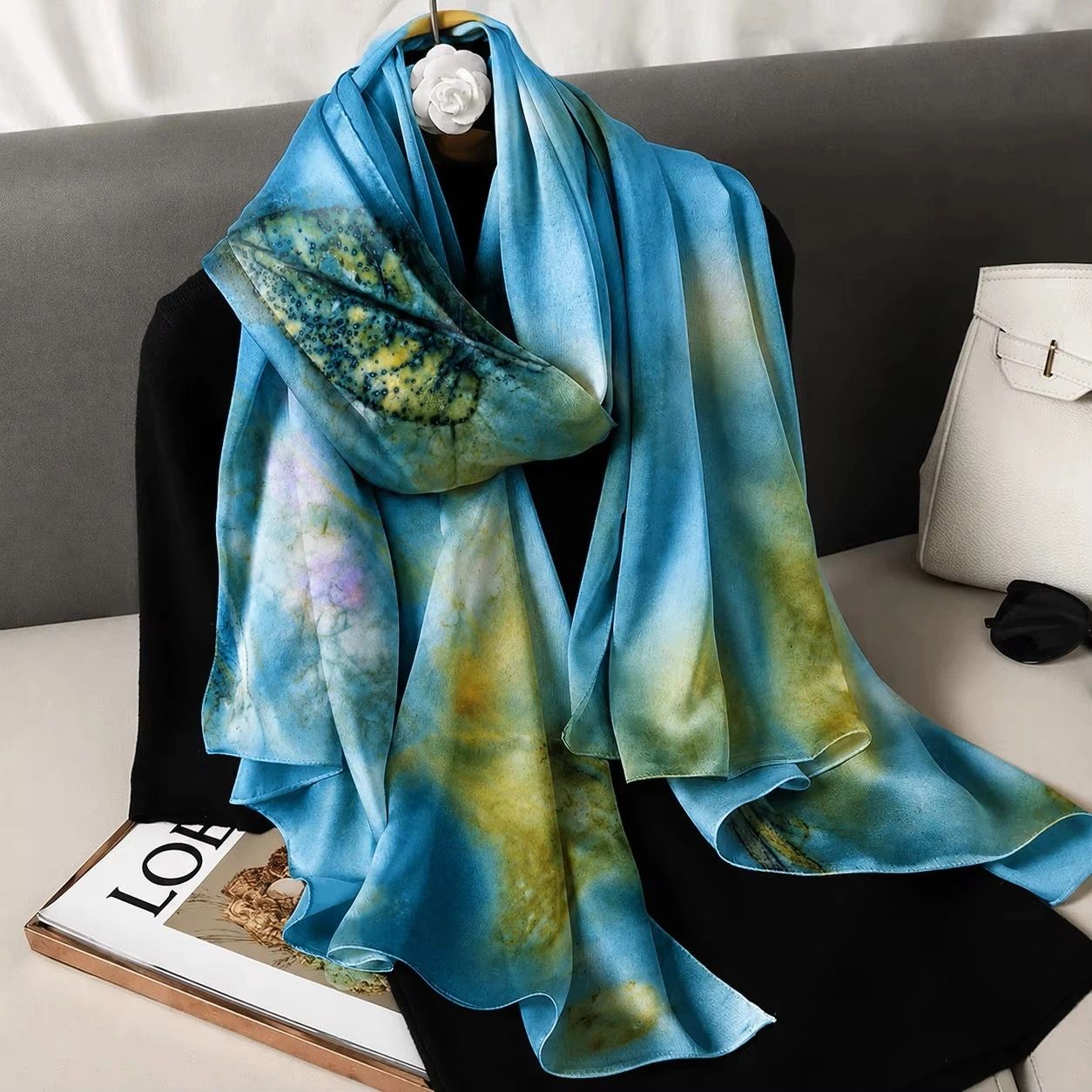 Blue and green silk scarf displayed on black fabric.
