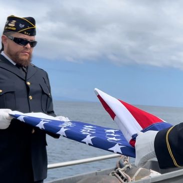 Honor detail Greg Seidel and Alonzo Lewis at sea doing a burial ceremony
