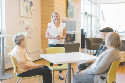 A caregiver engaging with elderly people in a cozy room.