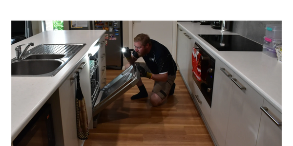 Photograph of man inspecting the inside of a dishwasher in the kitchen of a home