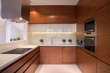 Modern kitchen design with warm wood cabinetry, white countertops, and integrated appliances
