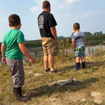 Man and two boys standing by manure lagoon after manure pumping and application in Northwest Ohio.