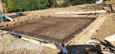 Construction site with steel reinforcement grid for concrete foundation.