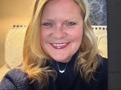 Smiling woman with blonde hair and a dark sweater.