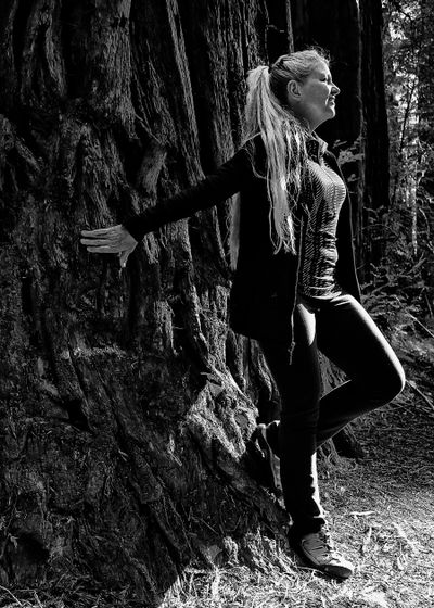 Cindy Seip, designer, photographer & part time mermaid, stands next to a gigantious red wood tree.
