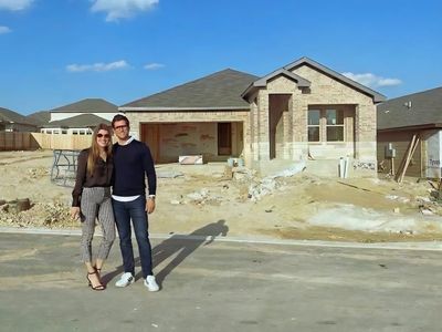 Couple standing on street in front of a house under construction.