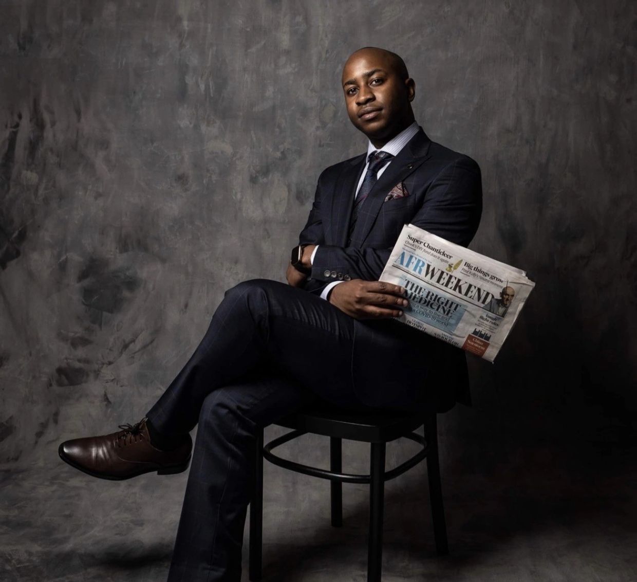 Man in a suit holding a newspaper.