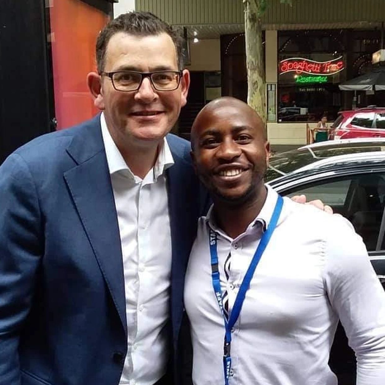 Two men smiling for a photo outdoors.