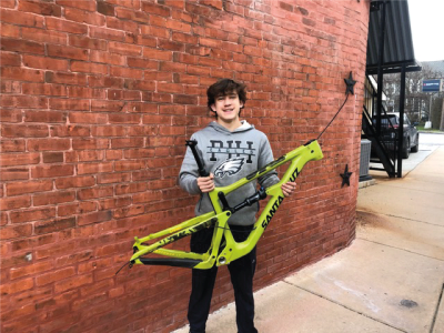Teen boy holding a bright green Santa Cruz bike frame.