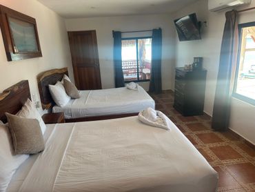 Cozy hotel room with two beds and ocean views through windows.