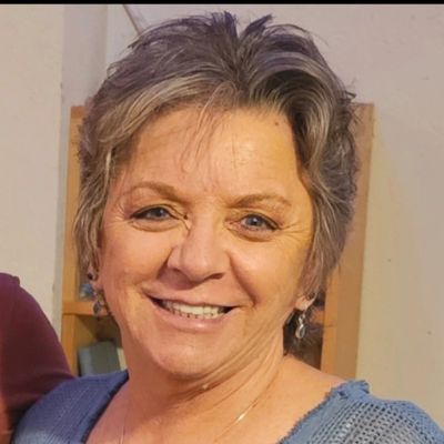 Smiling older woman with short hair and blue sweater.