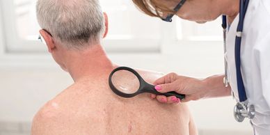 An elderly man getting a skin check.