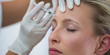 A woman getting a botox injection in her forehead.