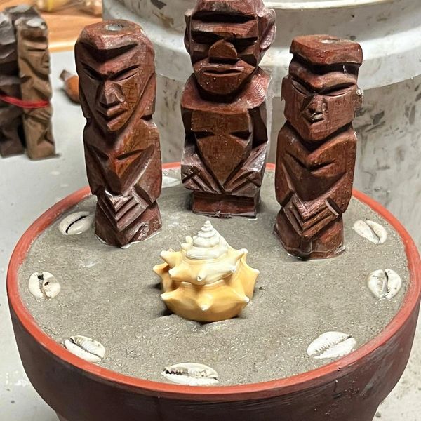 Figuras de madera y conchas en un recipiente con arena.