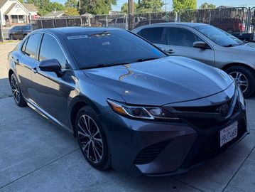 Sleek gray sedan parked in a sunny driveway next to another car.