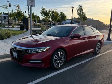 A red Honda sedan parked on a street during sunset.